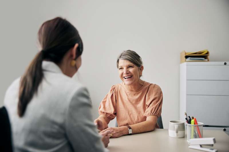 Older female client happily talking to a female audiologist